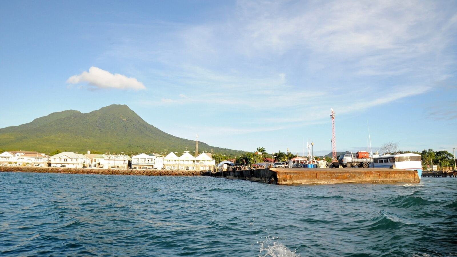Charlestown pier on Nevis with Nevis Peak behind, seen from a boat crossing from St Kitts