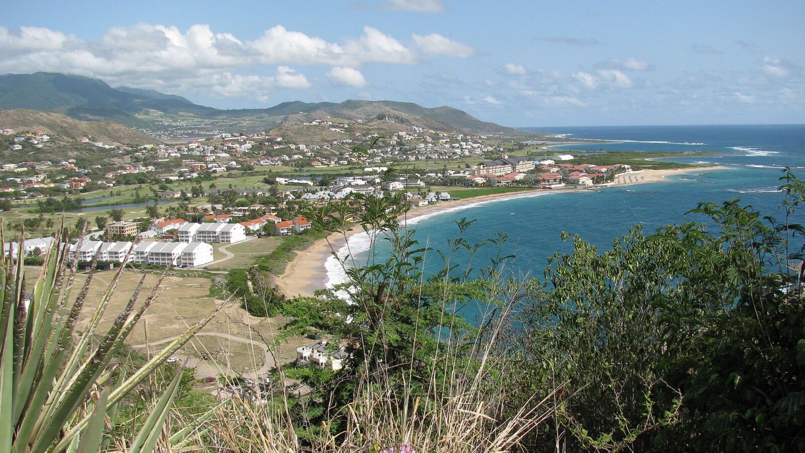 North Frigate Bay beach in St Kitts with hotels and condos along the shore, seen from the hill above